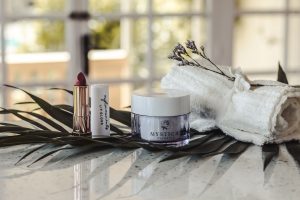 transparente Etiketten 50 x 25 mm mit schwarzem Druck auf einem Creme-Tiegel 50 ml für selbstgemachte Kosmetik. Daneben steht ein Lippenstift mit Lippenstifthülse. Die weiße Hülse ist mit einem durchsichtigen Etikett im Format 50 x 15 mm beklebt. Der Druck ist verspielt und gut lesbar.